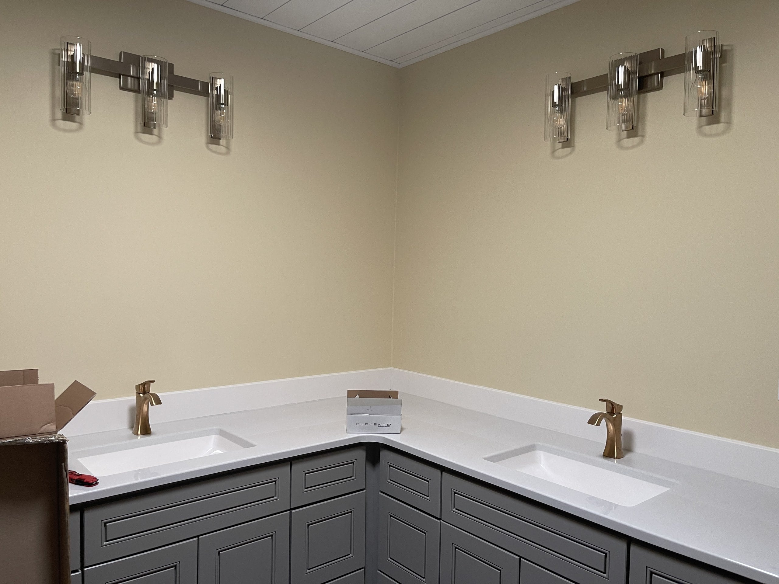 Bare bathroom wall above a double vanity before mirror hanging, Dakota County handyman service